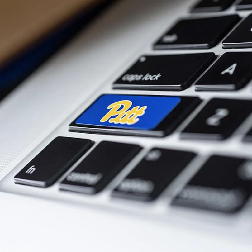 Key with Pitt script logo on laptop keyboard.